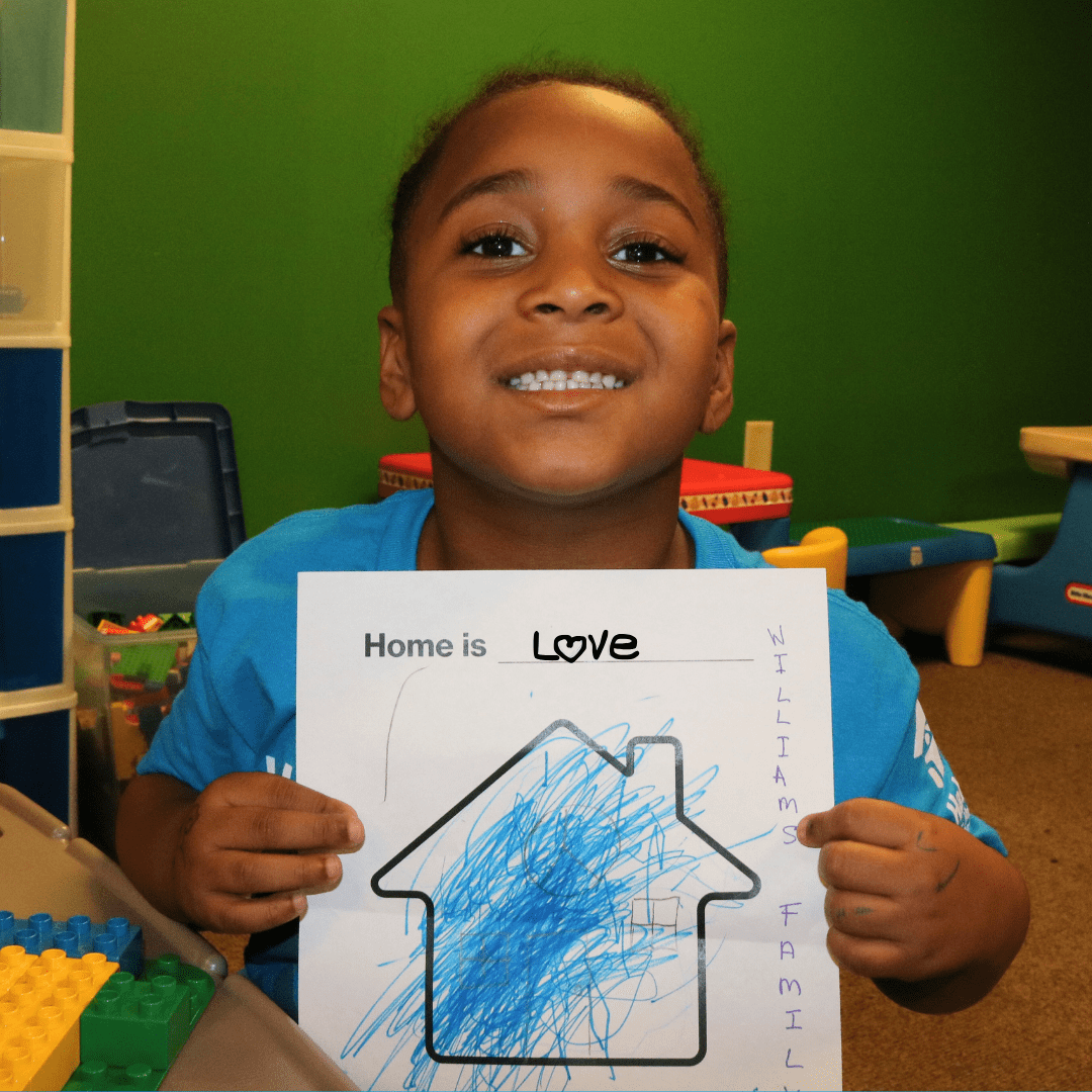 Bishop Drawing Bishop smiling while holding up hand drawn picture of future home